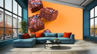 Chocolate brownie dessert with almond nut, chocolate glaze on an orange background. Wall mural