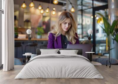 Female business employee in a purple suit uses a laptop Wall mural