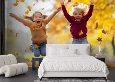 Two young children are jumping in the air and surrounded by falling leaves Wall mural