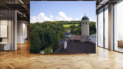 A clock tower with a dome and a cross on the roof. Church near the castle. In the background nature and blue sky with clouds. Wall mural