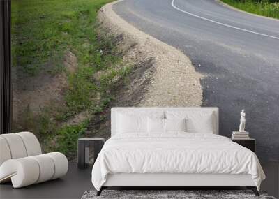 View to a winding new asphalt road in a rural area. Gravel roadside, ditch for rainwater. Latvia.  Wall mural