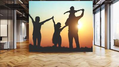 Silhouette of a family comprising a father, mother and two children happy family the sunset.Concept of friendly  Wall mural