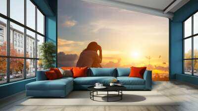 Silhouette of woman praying over beautiful sky background Wall mural