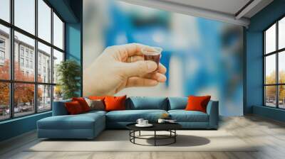 Hands hold a red wine cup in Holy communion Wall mural