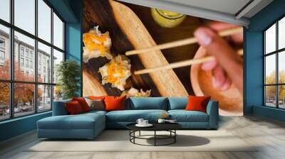 a hand tries to take dimsum from a wooden bowl using chopsticks Wall mural