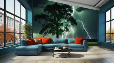 A lone tree beautifully illuminated by multiple Lightning bolts under the dark thunderstorm sky at night. Wall mural