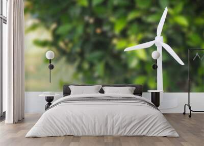 wind turbine or windmill on the white table with blur green tree using for energy background. Wall mural