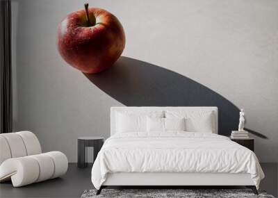 a delicious, juicy and healthy apple is illuminated by the sun and casts a long shadow on a stone surface.  Wall mural