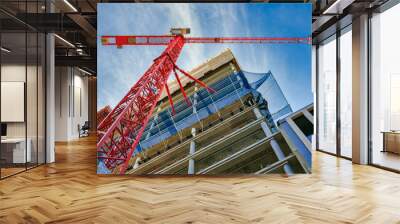 Highrise Building Site in Berlin. Looking up at the construction site of a high-rise building with red crane in the foreground. Wall mural