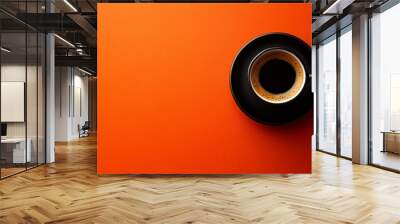 A cup of coffee with a black saucer on a bright orange background. Wall mural