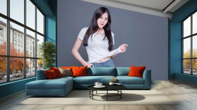 An Asian woman takes a fashion photo in a photo studio using a gray background. This image has a copy space. Wall mural