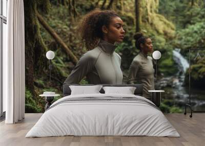 Three women are standing in front of a waterfall, wearing matching workout clothes. Scene is energetic and active, as the women appear to be ready for a workout or outdoor activity Wall mural