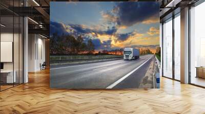 Cargo truck driving through landscape at sunset Wall mural