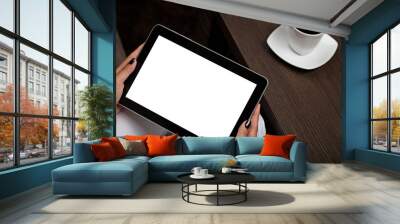 Someone holding digital tablet with blank screen next to table with cup of coffee. Wall mural