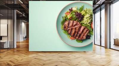 top view of medium pork steak with salad on plate isolated on pastel background Wall mural