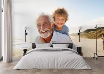 Happy grandfather joyfully piggybacking his cute little grandson on the beach Wall mural