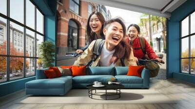 Happy group of young Japanese people with backpack riding a bike in Amsterdam. Life style concept with friends having fun together on summer holiday Wall mural