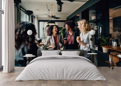 Happy positive female colleagues joking and laughing during coffee break in work place. Smiling business team talking, having fun and enjoying conversation in the office Wall mural