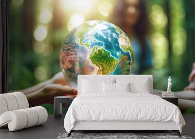 Human hands holding glass earth in green forest with sunlight. Environment, save the World, earth day, ecology, and Conservation Concept. Wall mural