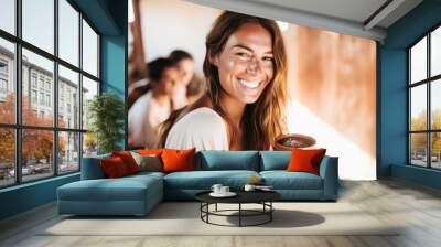 Portrait of a happy and smiling yoga teacher on Ibiza island, holding cacao drink in ceramic cup. Blurred people in the background Wall mural