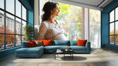 Portrait of a happy smiling pregnant Indian woman sitting by the window, concept of motherhood, expecting baby and parenthood Wall mural