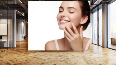 Portrait of a young smiling woman touching her flawless glowy skin on soft white background, skincare concept Wall mural