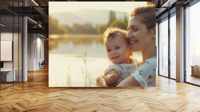 Smiling mother holding adorable toddler child outdoors,  beautiful nature landscape with lake in the background Wall mural