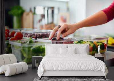 Woman putting cut fruit and vegetable into glass containers, closeup Wall mural