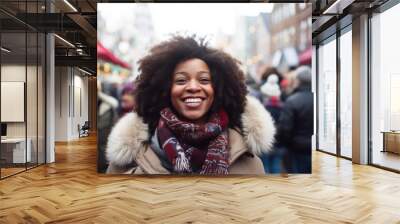 Young smiling african american woman in winter clothes at street Christmas market in Amsterdam Wall mural