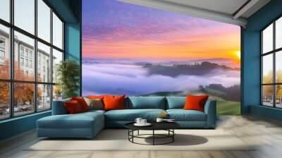 Sunrise breaking through morning fog over rolling hills, foggy weather, peaceful dawn Wall mural