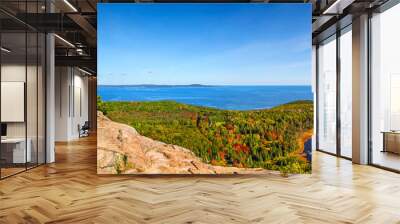 Female hiker standing on ledge enjoying view of water from Beehive Trail in Acadia National Park Wall mural