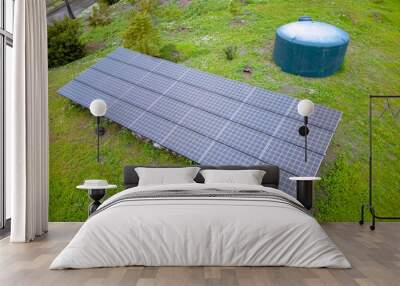 Fallbrook, California- Solar panels and water tank on a green grassland in a farm. There is a driveway on the top left of the solar panel and cistern tank. Wall mural