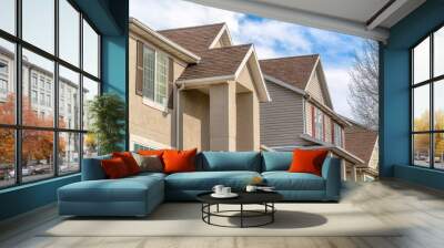 Houses with gable roofs and beige exterior walls against blue sky and clouds Wall mural