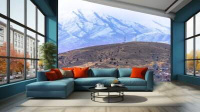 Panorama of houses and hilly terrain with magnificent snowy mountain background Wall mural