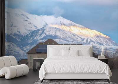 Solar panels on roof of home with lake and snowy mountain background in winter Wall mural