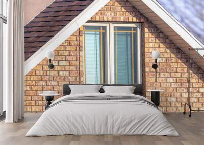 Square frame Close up of a home exterior with sunlit pitched roof over window and brick wall Wall mural