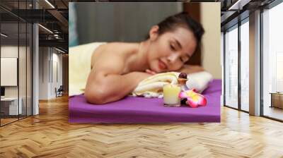 Asian woman enjoying a salt scrub massage at spa. Wall mural