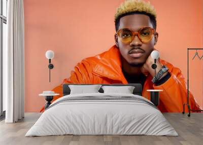 A man in an orange jacket and glasses is sitting on a chair Wall mural