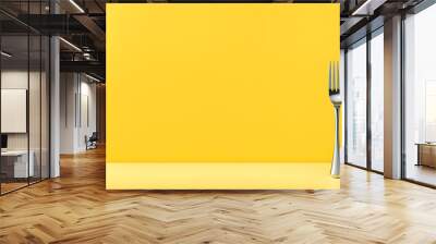 A yellow background with a fork and knife on it Wall mural