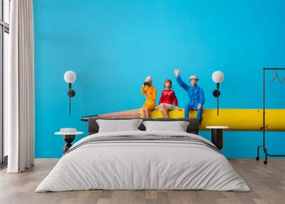 Miniature people, man and woman sitting on yellow pencil using as business and social concept Wall mural