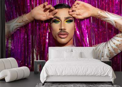 portrait of beautiful young man in drag queen makeup looking at camera and colorful background Wall mural