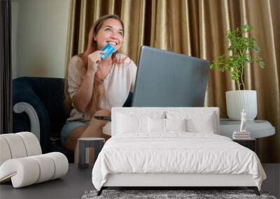 Joven mujer sonriente comprando algo online con su tarjeta de credito Wall mural