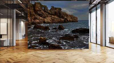 Seascape of a rocky coast that juts out into the Mediterranean Sea, at sunset, with a cloudy sky Wall mural