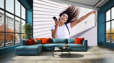 African woman listening to music with earphones and smartphone Wall mural