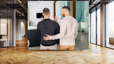 Gay couple holding hands looking at their new home together. Wall mural