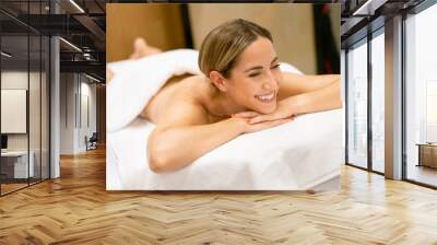 Middle-aged woman lying on a beauty parlour couch for a relaxing massage. Wall mural