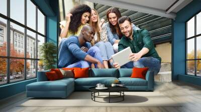 Multi-ethnic group of young people looking at a tablet computer Wall mural