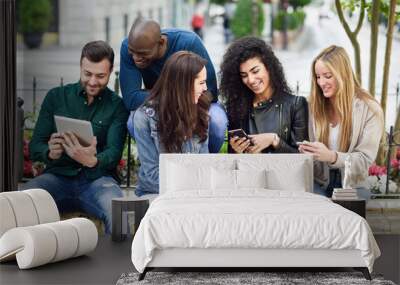 Multi-ethnic young people using smartphone and tablet computers outdoors Wall mural