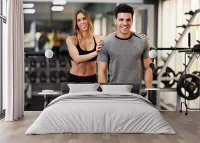 Personal trainer helping a young man lift weights Wall mural