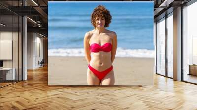 Smiling woman in red bikini on beach Wall mural